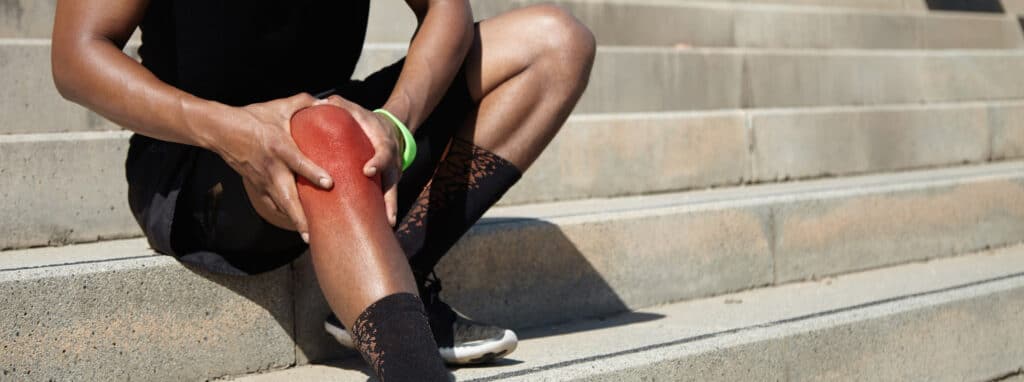 An athlete holding his knee in pain.