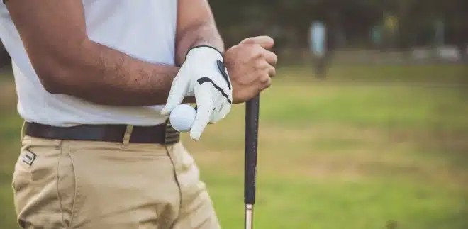 A golfer stands holding a club and golf ball. Golfer's Elbow is an overuse injury that doesn't just effect golfers, though. It can be seen in those who lift weights as well.