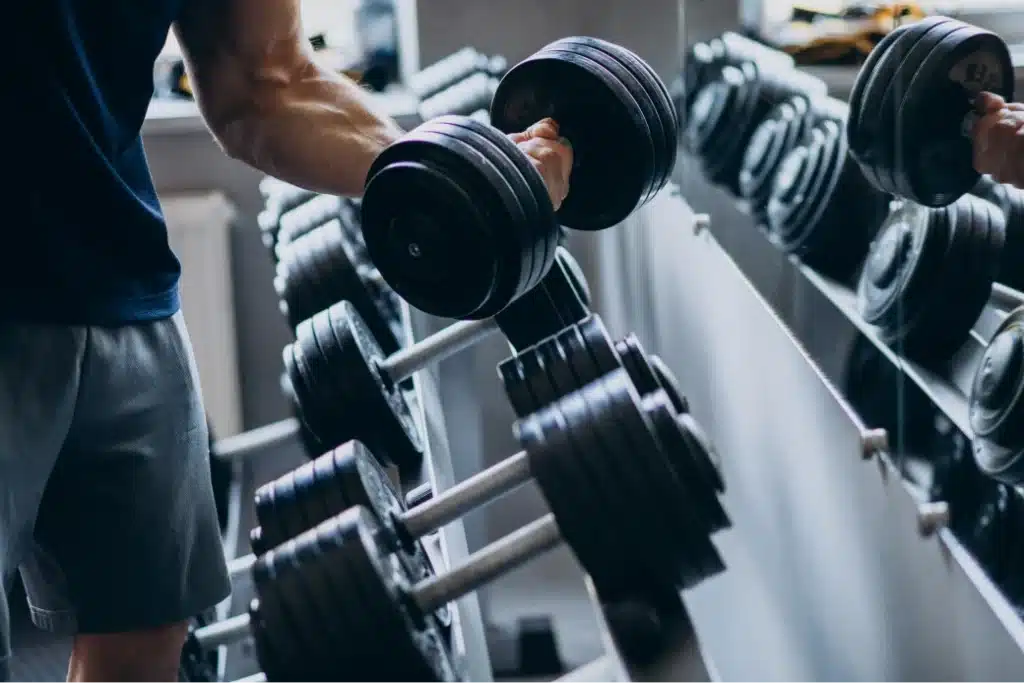 A man weight lifting in the gym with dumbells.